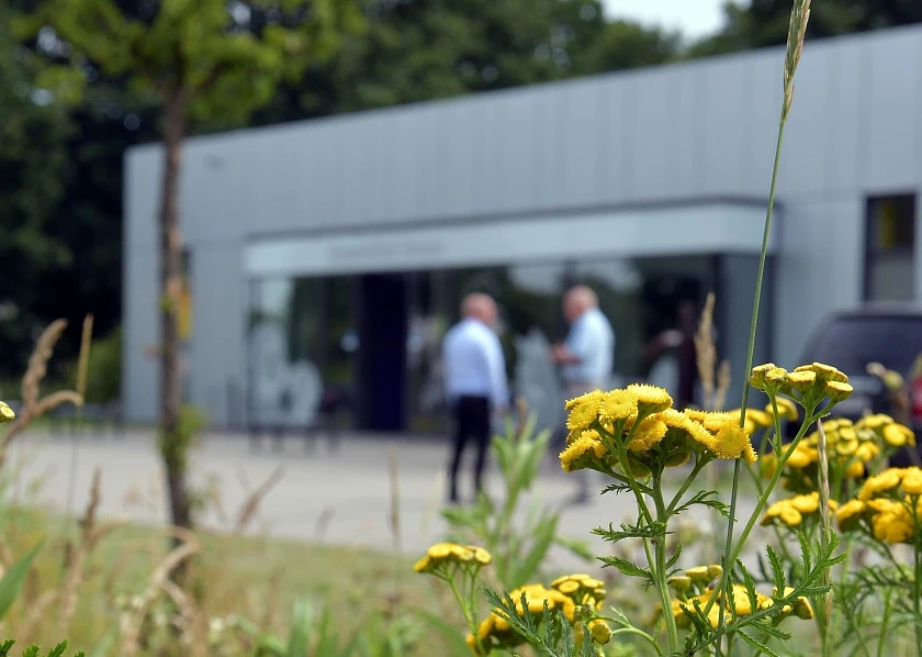 Naturnah gestaltetes Firmengelände mit Parkplatz im Vordergrund