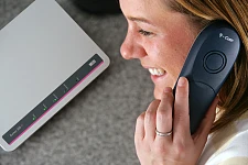 Eine Frau am Telefon eines Telekom-Telefons mit einem Router im Hintergrund