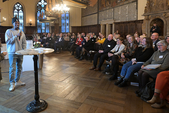 Alpha Oumar Diallo (l.), Auszubildender bei Amco Metall Service GmbH, berichtet beim Senatsempfang in der Oberen Rathaushalle von seinen Erfahrungen.