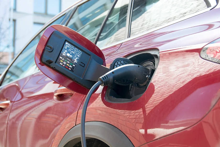 Nahaufnahme eines roten Elektroautos beim Laden an einer Ladesäule auf dem Firmengelände.