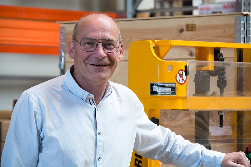 Uwe Gernhold steht in einer Produktionshalle neben technischen Anlagen und blickt in die Kamera.
