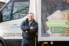Ein Mitarbeiter steht vor einem umweltfreundlichen Lieferfahrzeug des Unternehmens.