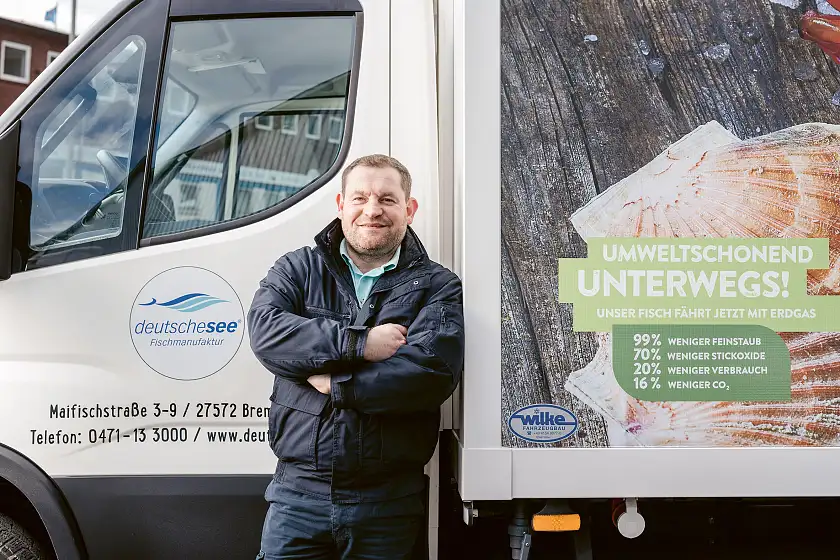 Ein Mitarbeiter steht vor einem umweltfreundlichen Lieferfahrzeug des Unternehmens.