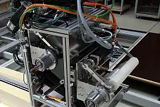 Industrielle Maschine mit Metallrahmen, Antriebsrollen, Riemen, Sensoren und Kabeln.