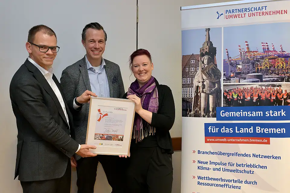 Jan-Hendrik Hunke und Heike Lau von der Bühnen GmbH & Co. KG nehmen die Auszeichnungsurkunde zum Klimaschutzbetrieb von Jan Fries, Staatsrat bei der Senatorin für Umwelt, Klima und Wissenschaft (links im Bild), entgegen.